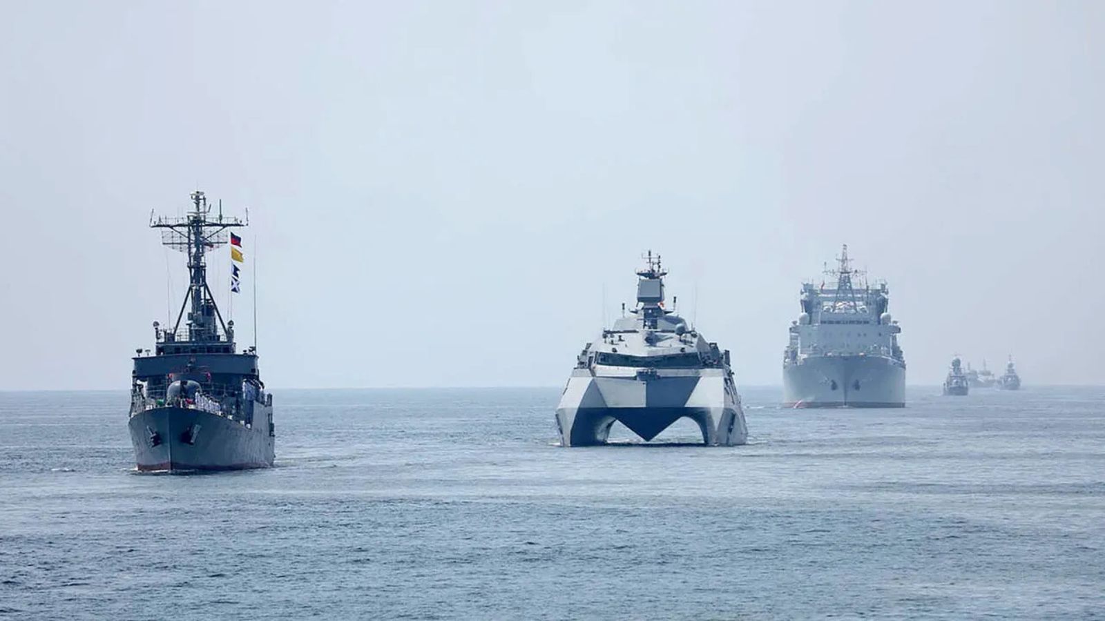 A formation of various Iranian naval warships sailing in the open sea.
