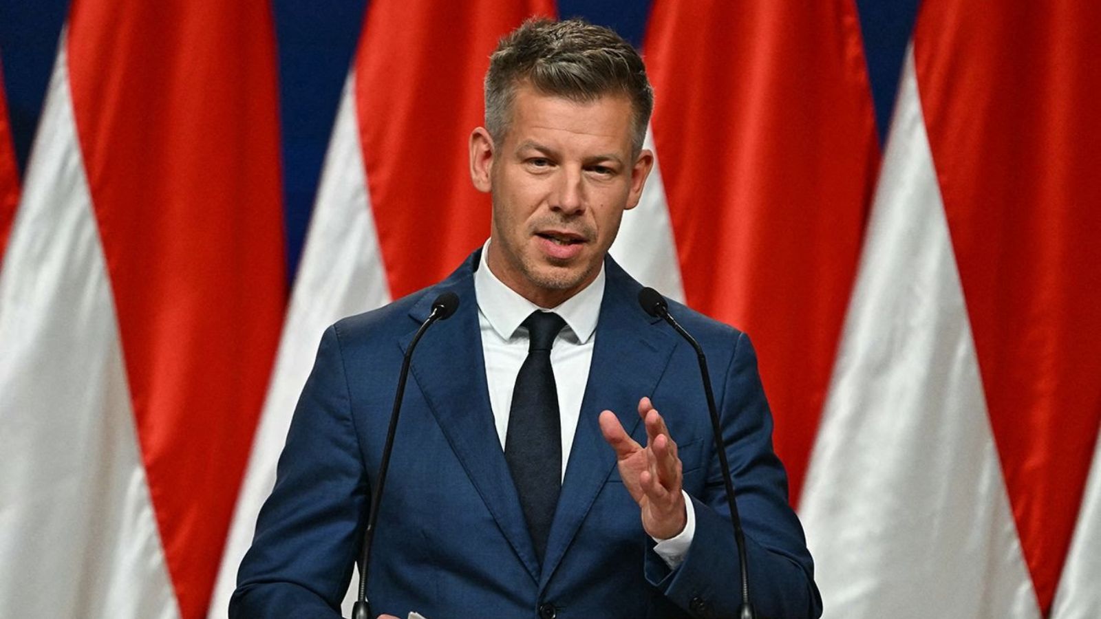 Péter Magyar giving a speech and gesturing with his hand in front of Hungarian flags