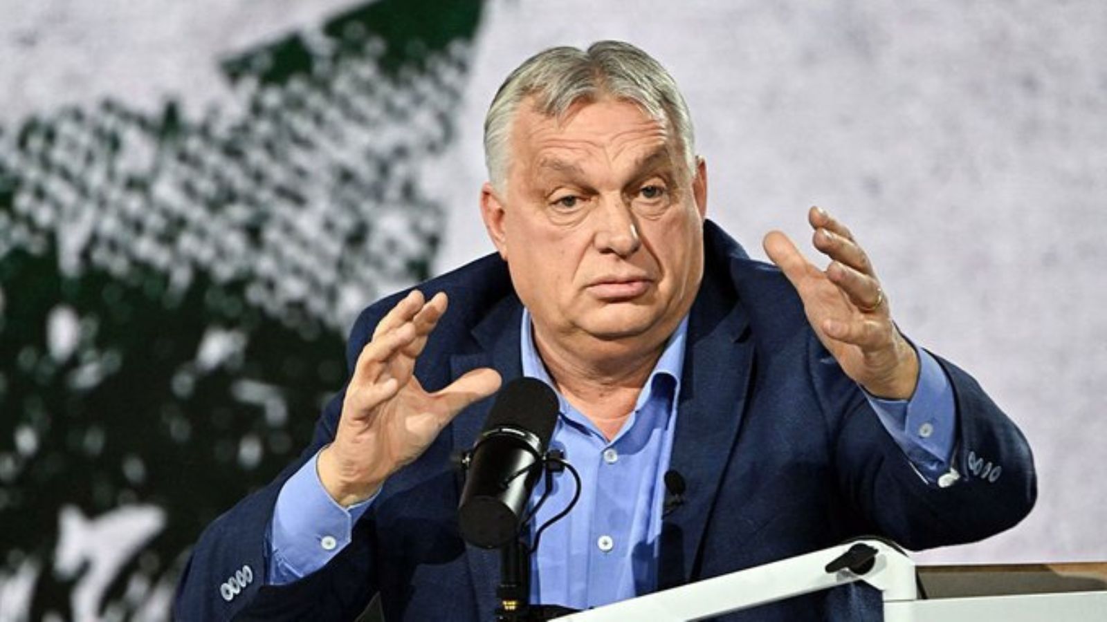 Hungarian Prime Minister Viktor Orbán gesturing actively during a public speech at a microphone.