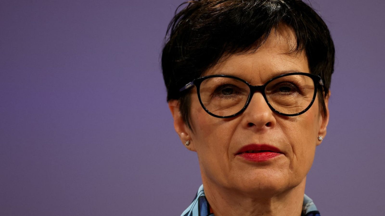 Portrait of Marta Kos, European Commissioner for Enlargement, against a purple background.