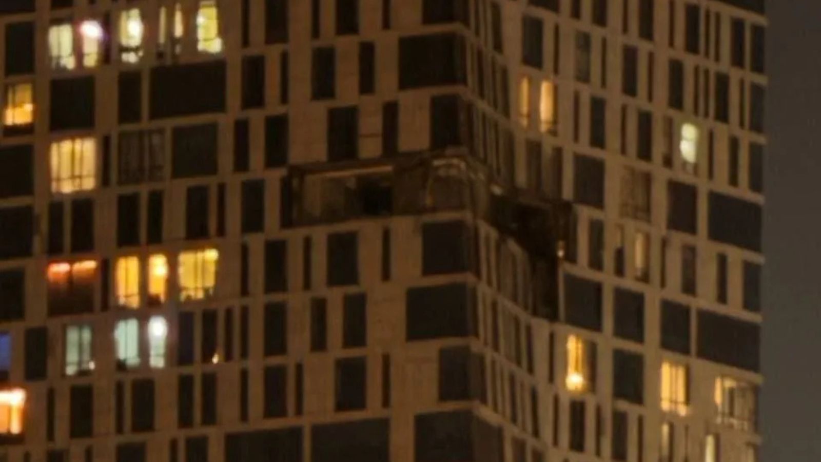 The damaged facade of a high-rise residential complex on Mosfilmovskaya Street with destroyed walls on the upper floors.